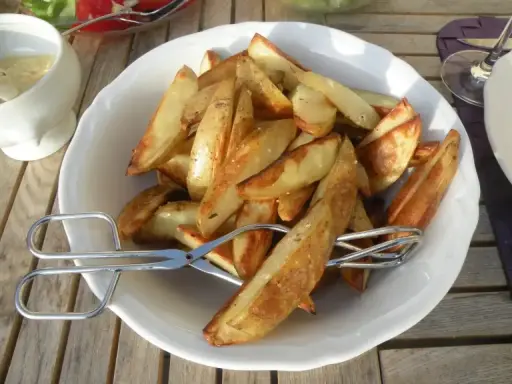 En skål med gyllene klyftpotatis i ugn, redo att serveras med en sallad och dipp. Perfekt tillbehör!