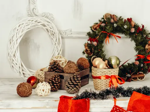 Jul inredning inspiration: en vit flätad krans, julgranskulor, kottar och en grön julkrans med torkad frukt.