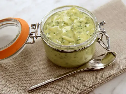En burk med krämig bearnaisesås, perfekt för ditt nästa bearnaise recept. En sked ligger bredvid.