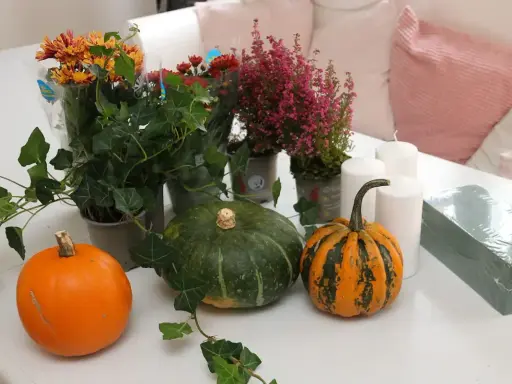 Förberedelser för att dekorera pumpa med höstblommor, ljus och murgröna.
