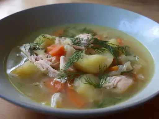 En närbild av en skål med värmande fisksoppa, full av potatis, morötter och dill. Ett perfekt fisksoppa recept för en kall dag.