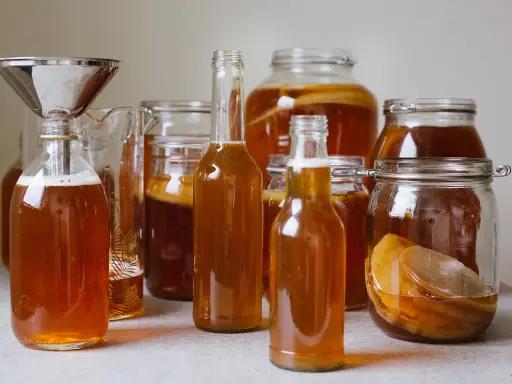 Flera flaskor och burkar med hemgjord kombucha, redo för andra jäsningen. Ett perfekt kombucha recept för hemmabruk.