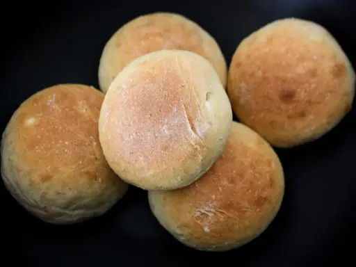 Fem nybakade frallor på en svart bakgrund. Perfekt för ett enkelt frallor recept.