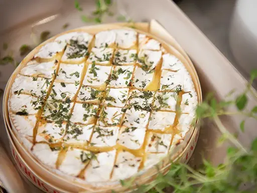 En härlig brie i ugn, gyllene och bubblande, toppad med örter. Perfekt för att doppa bröd i.