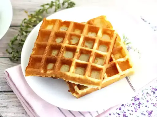 Två gyllene frasvåfflor på en tallrik, redo att avnjutas. Ett perfekt recept för frukost eller fika.