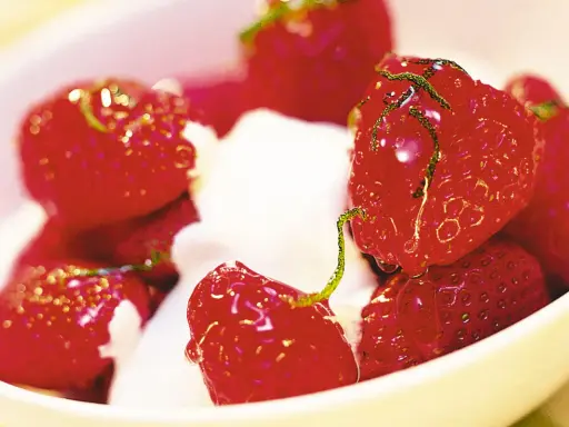 En skål med saftiga, limemarinerade jordgubbar och vispad grädde. En härlig sommardessert.