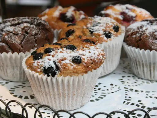 Färska muffins med blåbär och choklad, pudrade med florsocker. Perfekt för ett enkelt muffins recept.