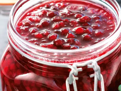 En burk med hemlagad lingonsylt, perfekt för ditt lingonsylt recept. Bären glänser i den söta lagen.