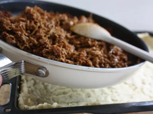 Köttfärs till tacopaj i långpanna. En sked ligger i pannan med den kryddiga färsen.