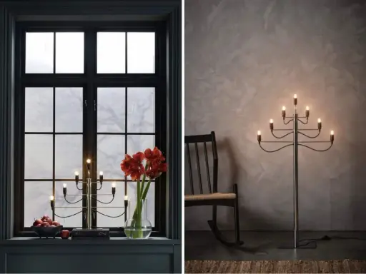 Två fina adventsljusstakar, en i ett mörkt fönster med amaryllis och äpplen, en annan som golvlampa bredvid en gungstol.