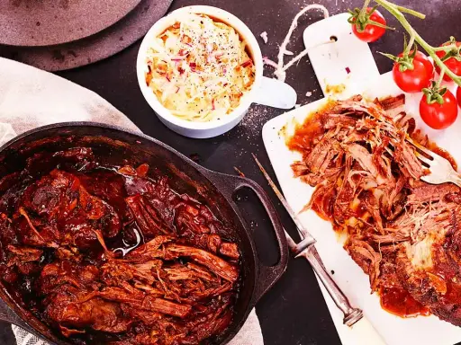 Saftigt pulled beef i en gjutjärnsgryta, serverat med krispig coleslaw och färska tomater. Perfekt för en mysig middag.