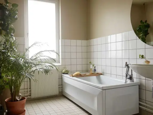 Ett ljust badrum med vitt kakel, ett badkar, en handfatskommod och gröna växter. Perfekt för att piffa upp badrummet med en grönskande känsla.