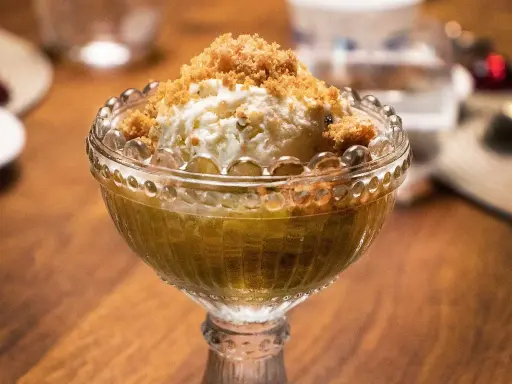 En skål med rabarberkompott och kardemumma, toppad med vaniljglass och smuldeg. En härlig dessert!
