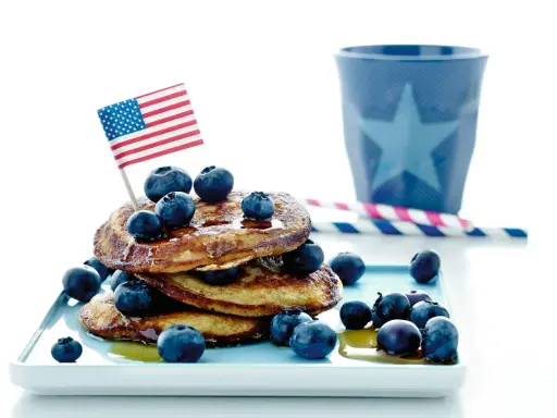 Amerikansk bananpannkaka recept med blåbär och en liten flagga. Perfekt för en festlig frukost!