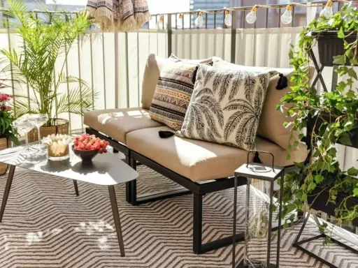 Mysig uteplats med soffa, kuddar, bord med vindruvor och växter. Perfekt för att styla uteplatsen.
