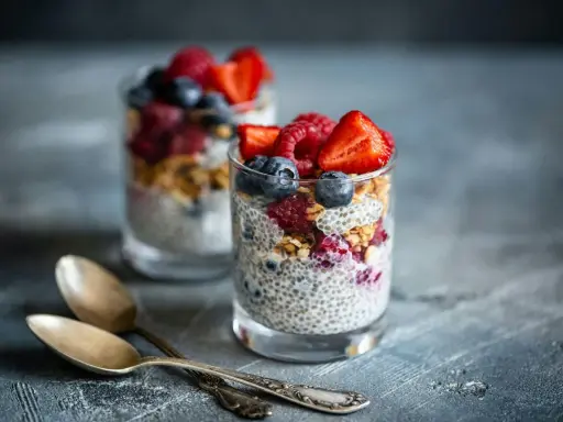 Två glas med chiapudding, toppade med bär och granola. Ett perfekt chiapudding recept för en hälsosam frukost eller mellanmål.