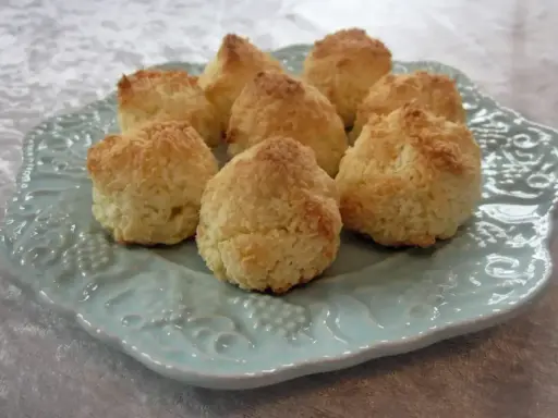 Små, gyllene kokostoppar på en vacker ljusblå tallrik. Perfekt för ett enkelt kokostoppar recept.