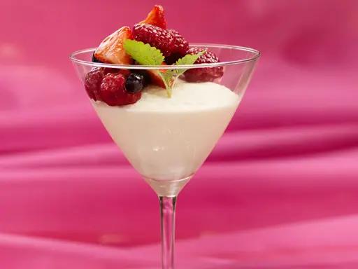 En elegant vit chokladmousse i ett martiniglas, toppad med färska bär och en myntakvist. En dröm för alla som älskar vit chokladmousse.