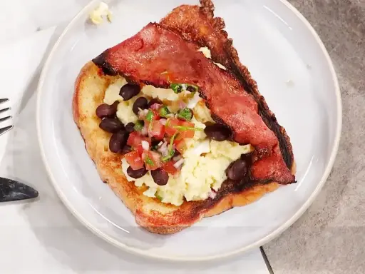 En tallrik med fattiga riddare toppad med äggröra, svarta bönor och salsa.