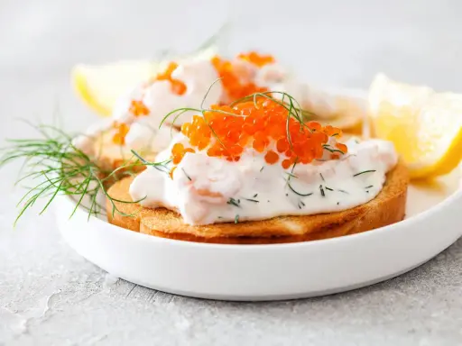 Toast Skagen med dill och rom på rostat bröd, garnerad med dillkvistar och citronklyftor.
