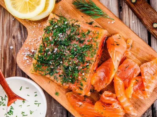 Njut av en bit gravad lax, toppad med dill och salt, serverad med citronskivor och en krämig sås.