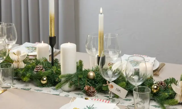 Vacker juldukning med granris, ljus och julgranskulor. En fin juldukning som skapar stämning.