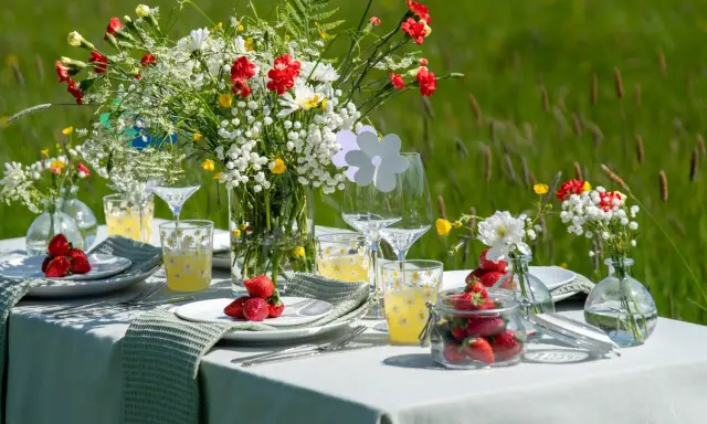 Vackert dukat bord med blommor och jordgubbar för att duka till midsommar.