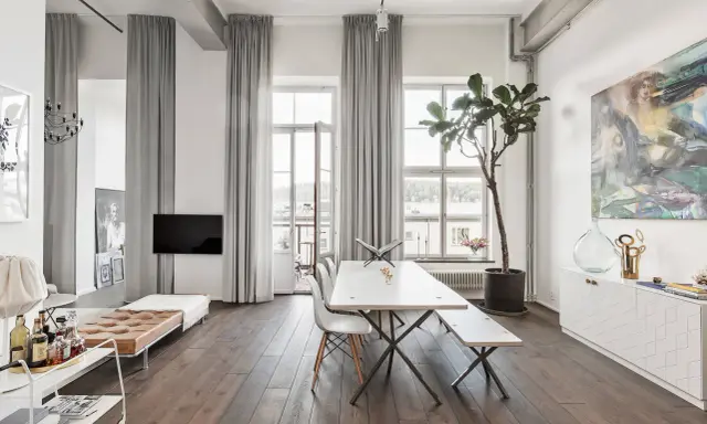 Grå gardiner bakom soffan skapar en ombonad känsla i det ljusa rummet.