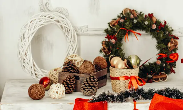 Jul inredning inspiration: en vit flätad krans, julgranskulor, kottar och en grön julkrans med torkad frukt.