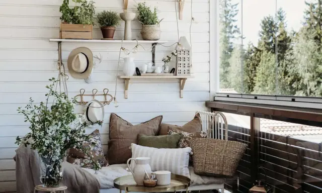 Mysig balkongdesign med kuddar, växter och en korgväska. En perfekt plats för avkoppling.