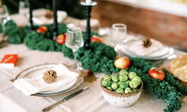 Vacker juldukning inspiration med grönt kale, äpplen och rosenkål. En rustik dukning som bjuder in till fest.