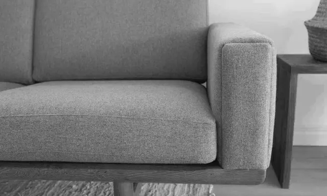 Grå soffa med trästomme, ett exempel på tidlös design möbler second hand.