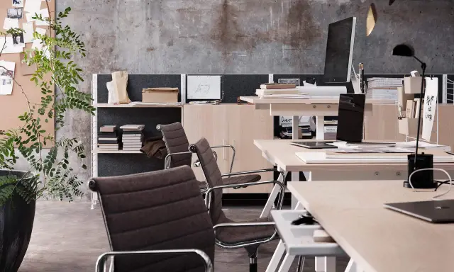 En modern arbetsplats med stolar, skrivbord, datorer och växter. En inspirerande miljö för kreativt arbete.