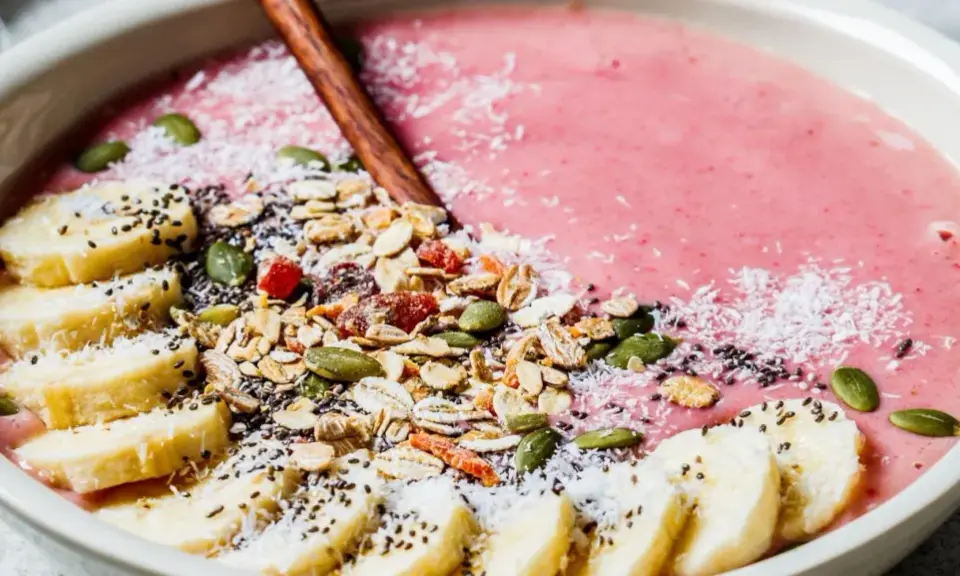 En rosa smoothie bowl med bananskivor, granola, pumpafrön, chiafrön och kokosflingor. En perfekt start på dagen!