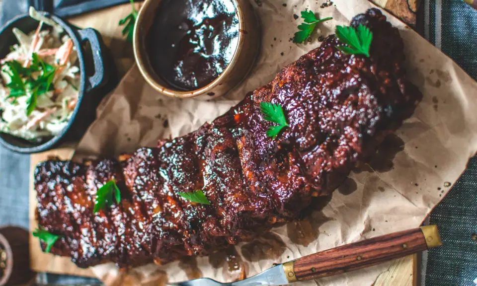 Saftiga spareribs i ugn, glaserade och serverade med en skål coleslaw och BBQ-sås. Perfekt för en härlig middag.