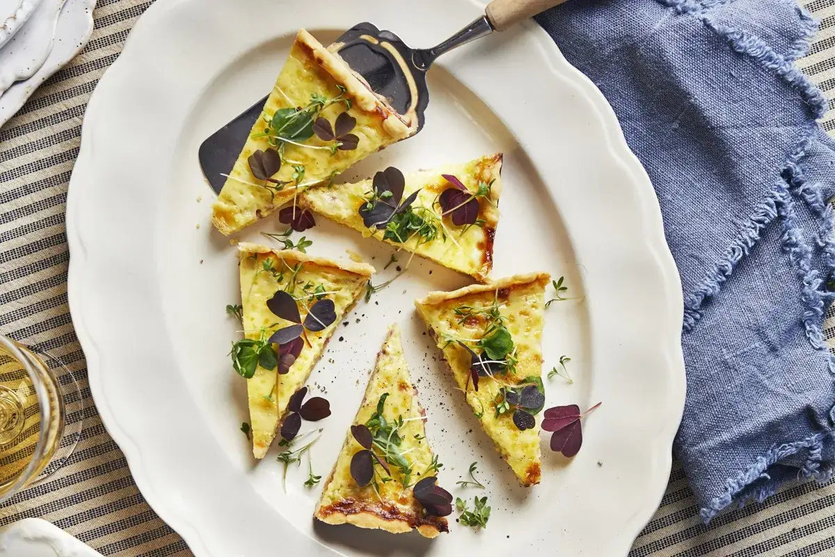 Läckra bitar av ostpaj, perfekt för ett enkelt ostpaj recept. Garnerad med färska örter och röda klöverblad.