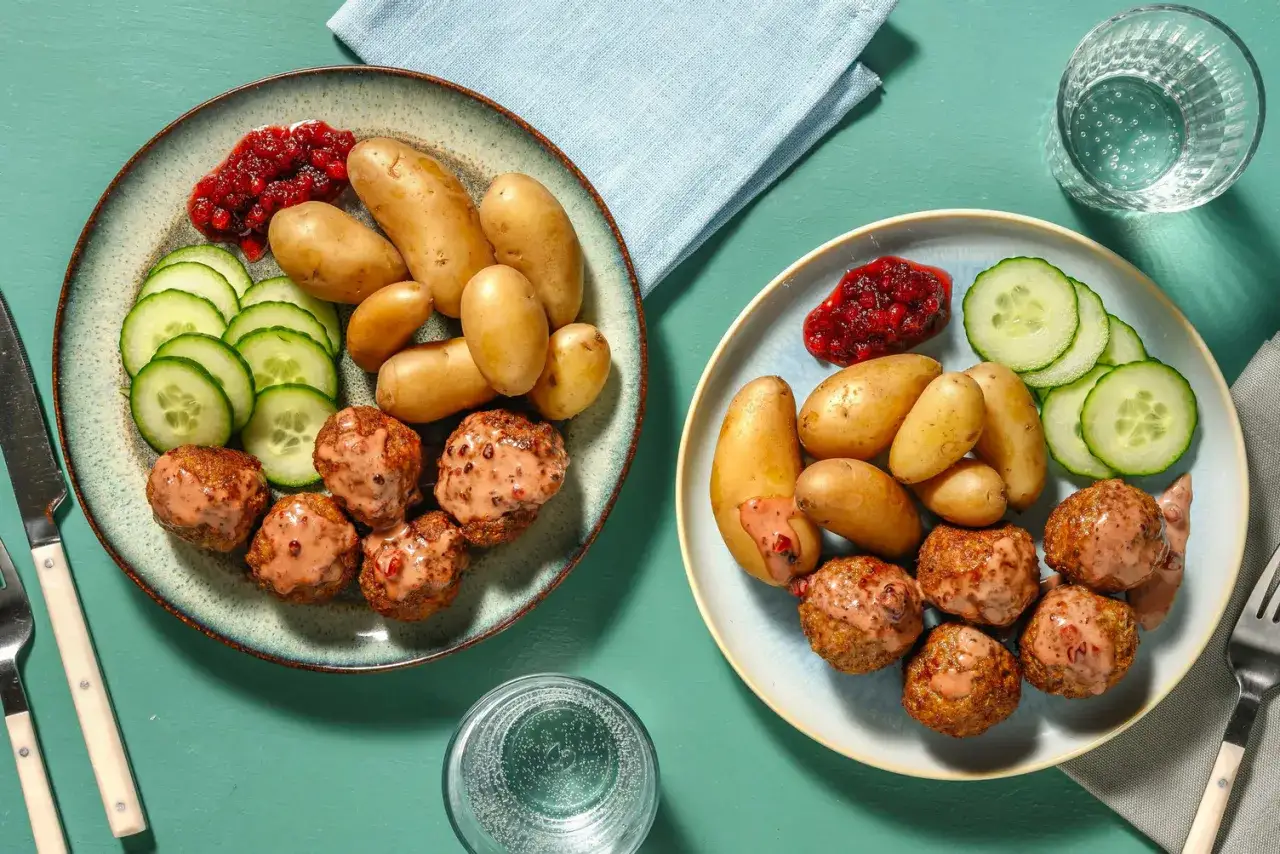 Två tallrikar med köttbullar, potatis, gurka och lingonsylt. Ett perfekt recept middag för hela familjen.