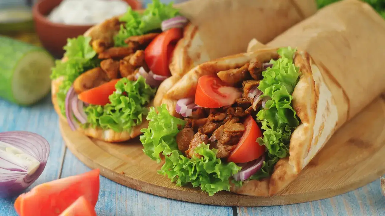 Två gyros med kött, sallad, tomat och lök inslagna i papper. Ett perfekt gyros recept för en snabb och god middag.