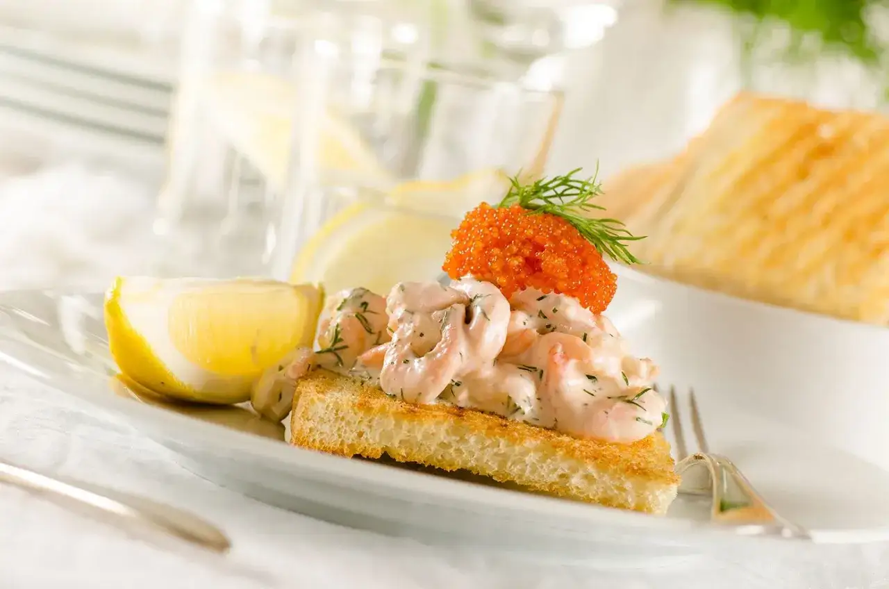 En härlig toast Skagen med krämiga räkor, rom och dill, serverad med citronklyfta.
