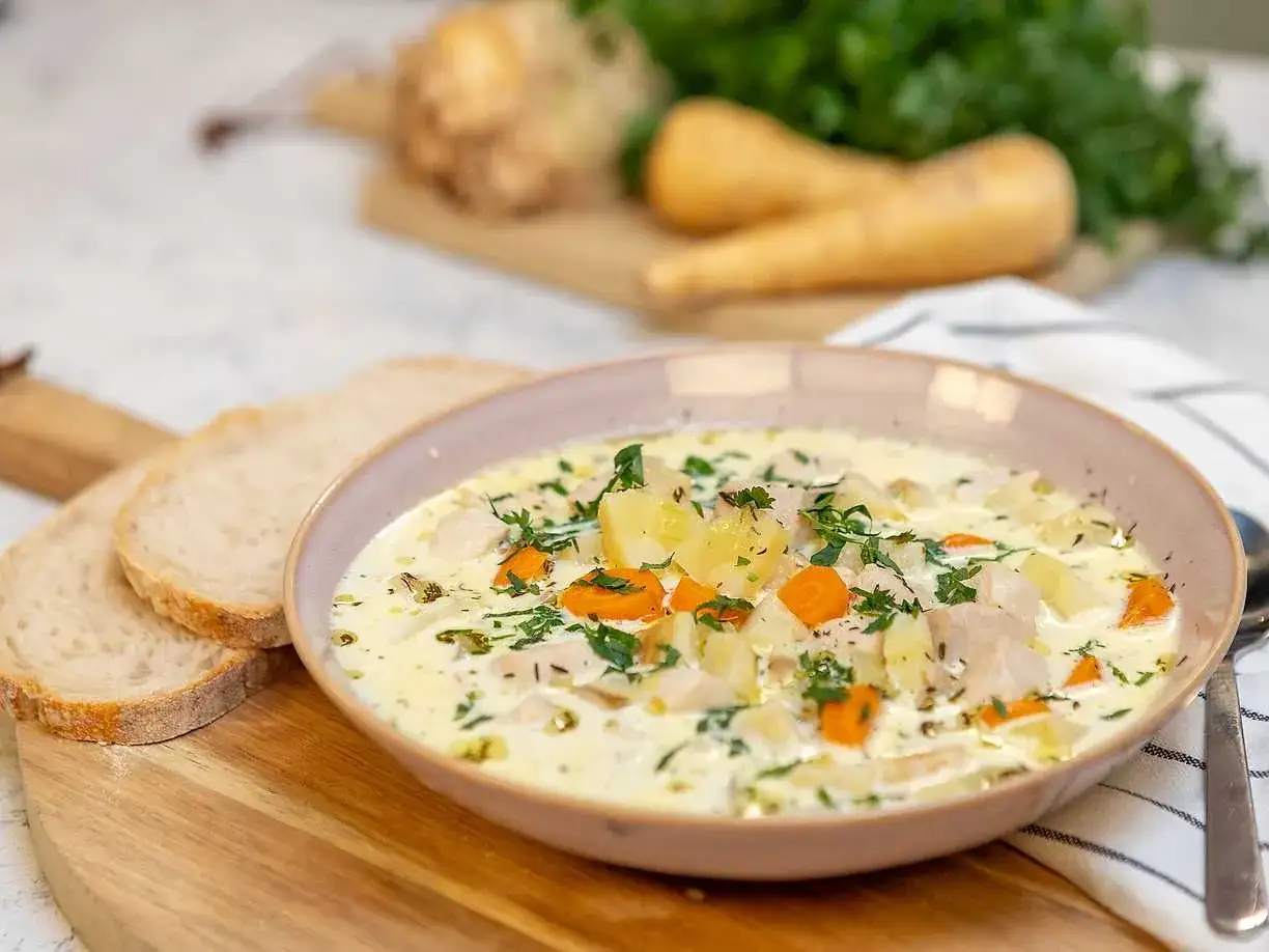 En krämig kycklingsoppa med rotfrukter och örter, perfekt för ett värmande kycklingsoppa recept. Serveras med gott bröd.
