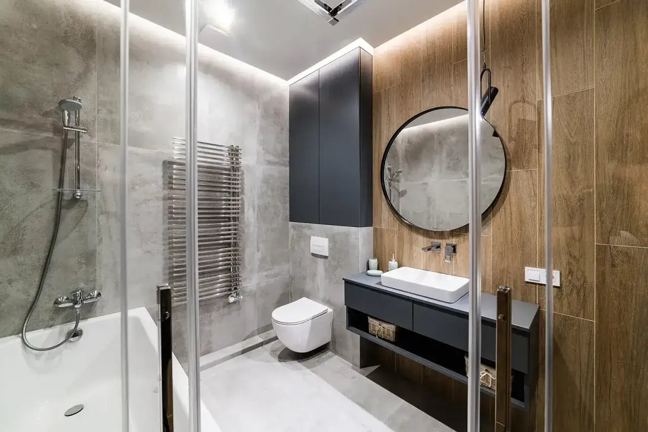 Modernt badrum med dusch, badkar, toalett och handfat. En stilren totalrenovering badrum med grå betongkakel och trädetaljer.