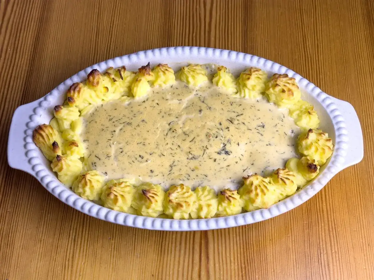 En krämig fiskgratäng med alaska pollock recept, toppad med spritsad potatis.