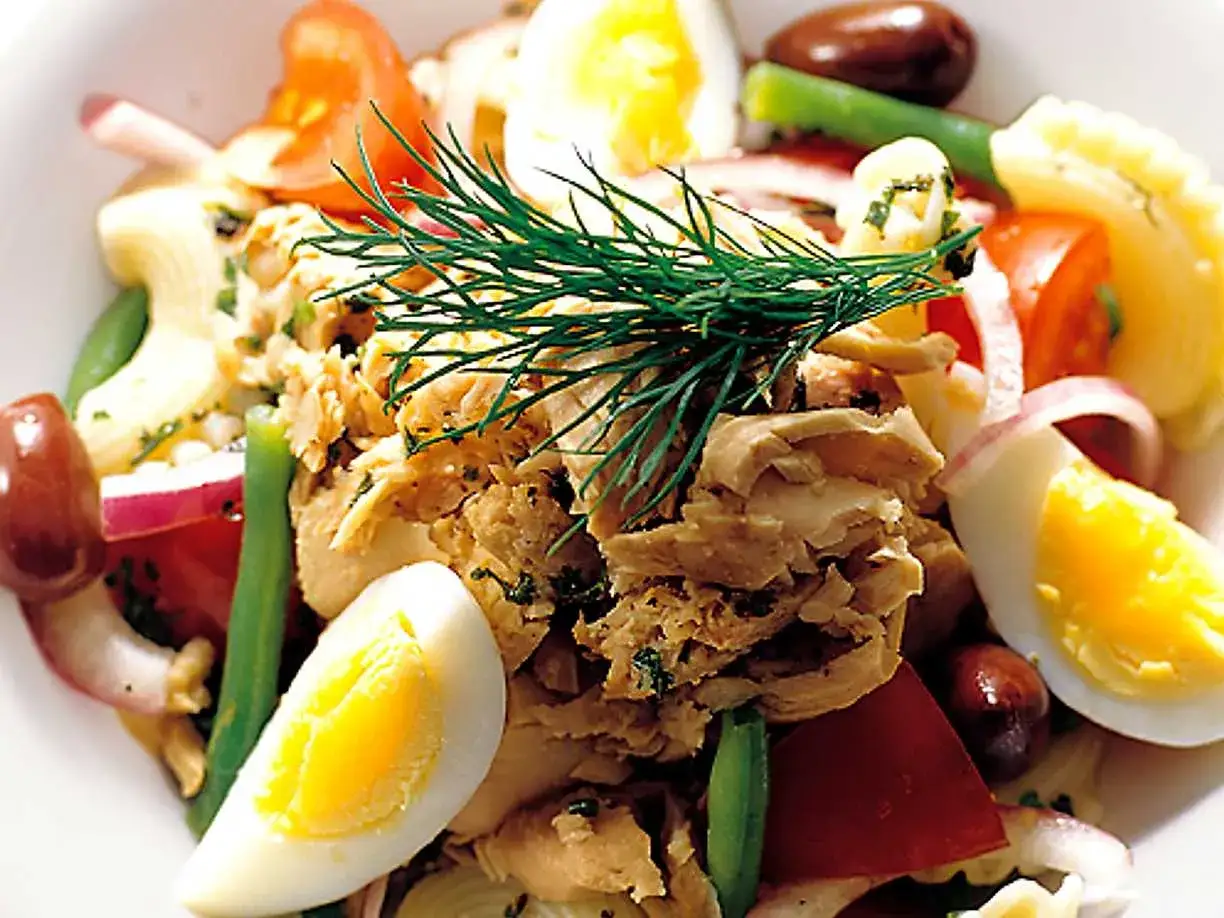 En härlig tonfisksallad med pasta, ägg, tomater, oliver och gröna bönor, toppad med dill.