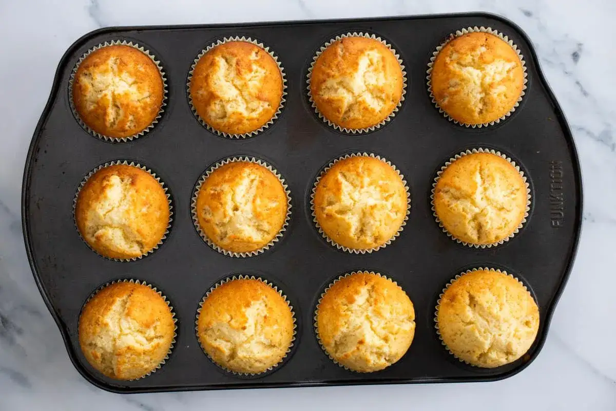 Tolv gyllene muffins i en form, redo att avnjutas. Ett perfekt muffins recept för fika.