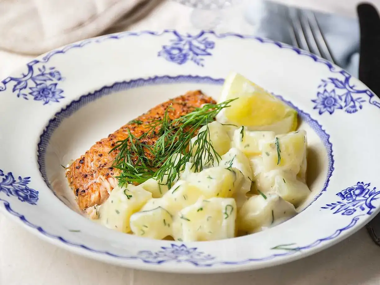 En bit stekt lax med citron och en generös portion krämig dillstuvad potatis.