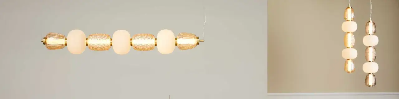 En elegant taklampa med detaljer i glas och mässing. Lampan har en unik design med flera glaskulor i olika former och texturer som ger ett mjukt och varmt ljus.