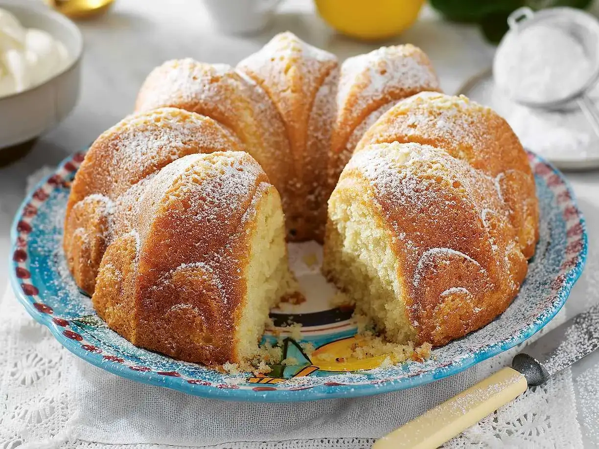 En saftig sockerkaka, pudrad med florsocker, ligger på en vacker blå tallrik. Perfekt för fikat!