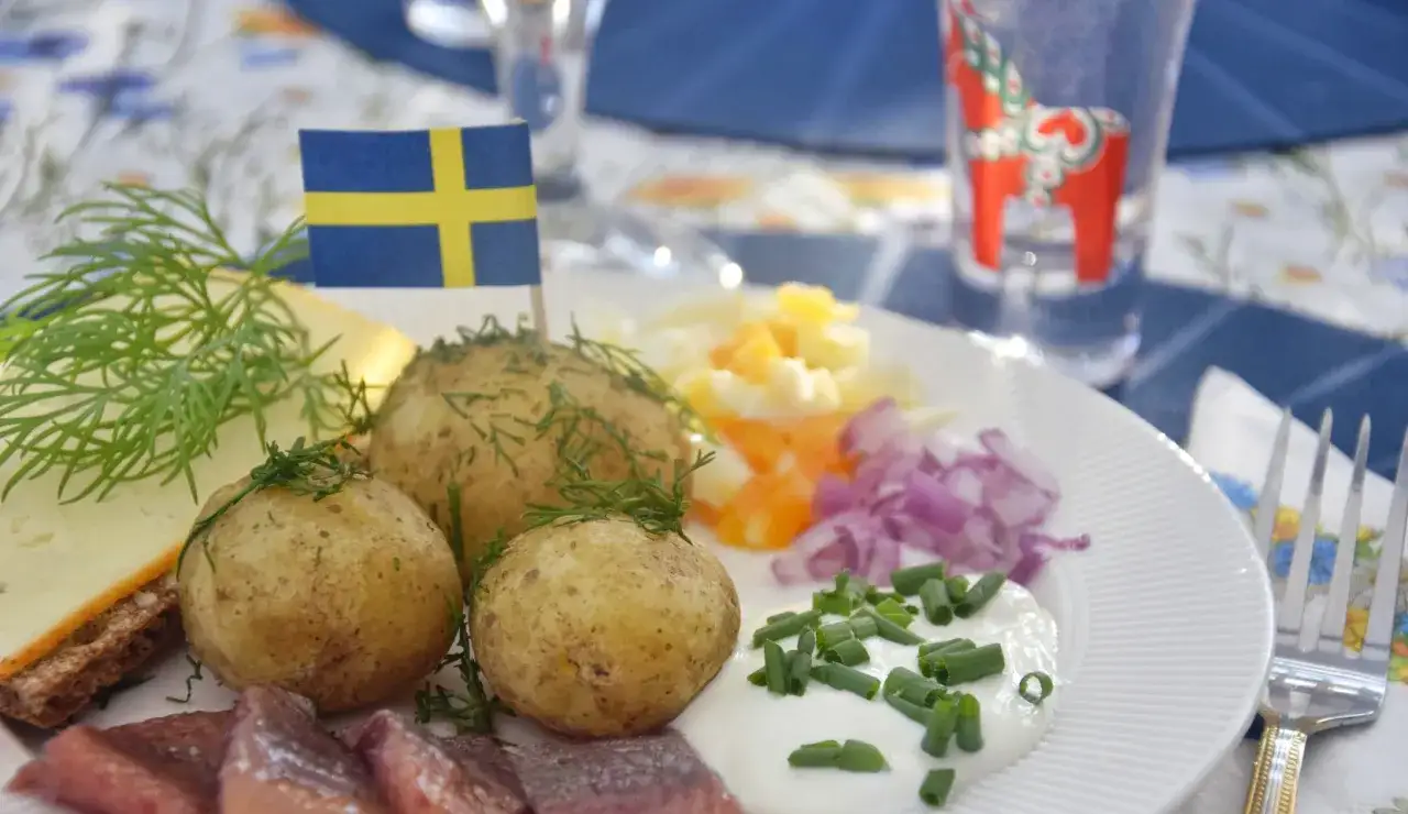 En härlig midsommar buffe med sill, färskpotatis, ost och gräddfil. En svensk flagga vajar stolt.