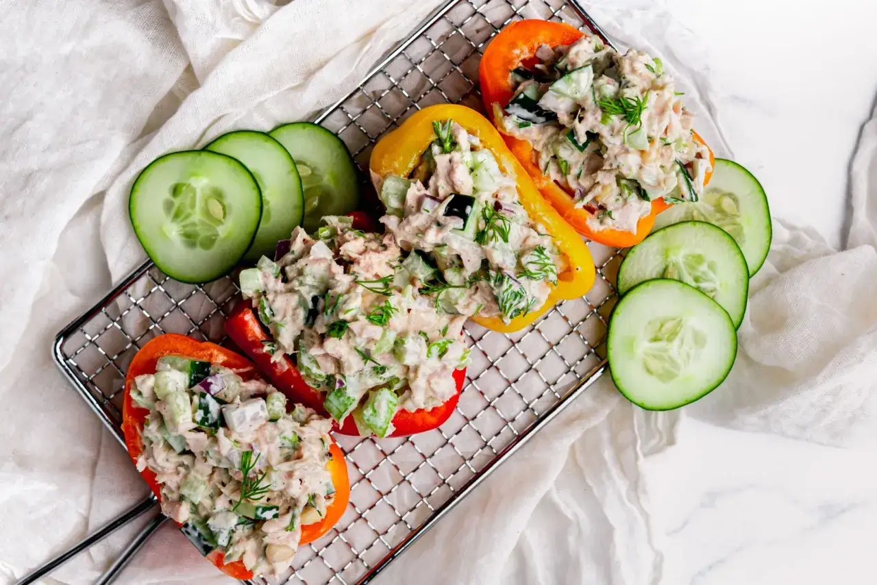 Fyllda paprikor med tonfisksallad, ett perfekt keto recept. Serveras med gurkskivor på ett galler.
