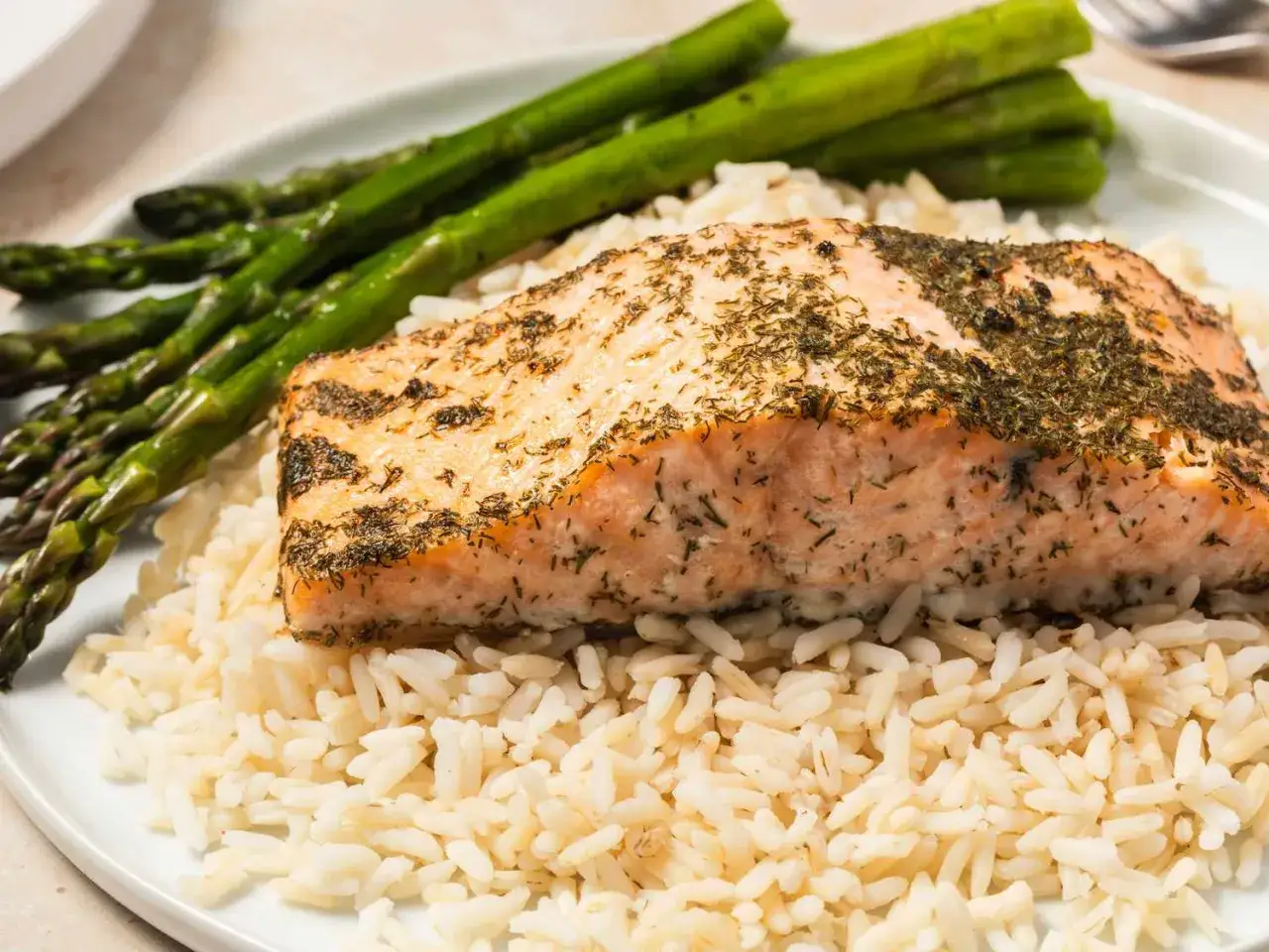 En saftig laxfilé med dill, serverad på ris med gröna sparrisar. Ett perfekt lax recept för en hälsosam måltid.